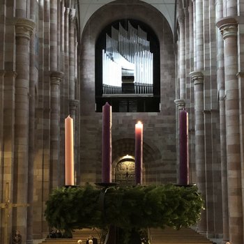 Großer Adventskranz mit einer brennenden Kerze, im Hintergrund der Innenraum des Doms mit Blick zur großen Domorgel