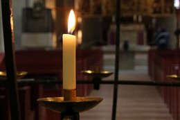 Brennende Kerze vor einem Gitter