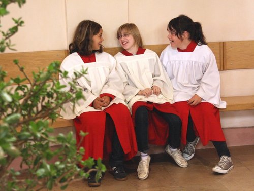 Drei Ministrantinnen sitzen lachend auf einer Bank