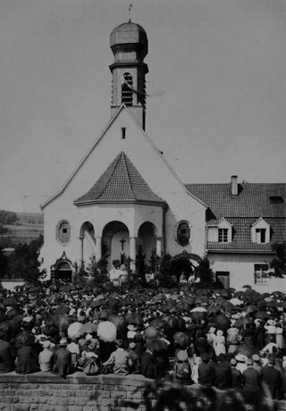 Ein schwarz-weiß Bild der Kirche Maria Rosenberg mit einer Menschenmenge davor.