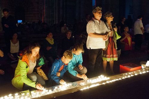 Menschen vor einer Reihe von Kerzen an den Stufen des Speyerer Domes vor dem Volksaltar.